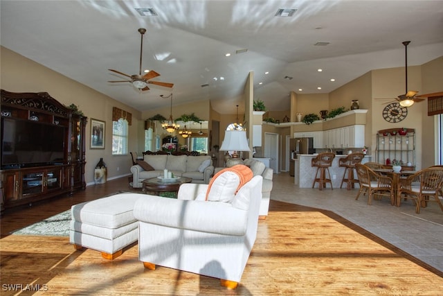 living area with visible vents, ceiling fan with notable chandelier, and high vaulted ceiling