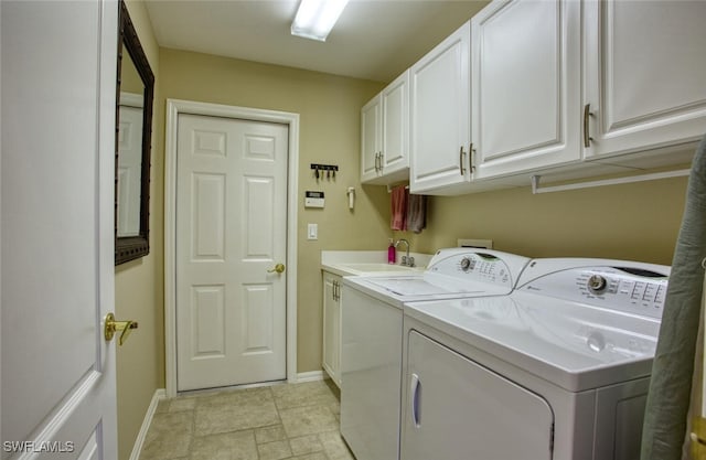 washroom featuring washing machine and clothes dryer, cabinet space, baseboards, and a sink