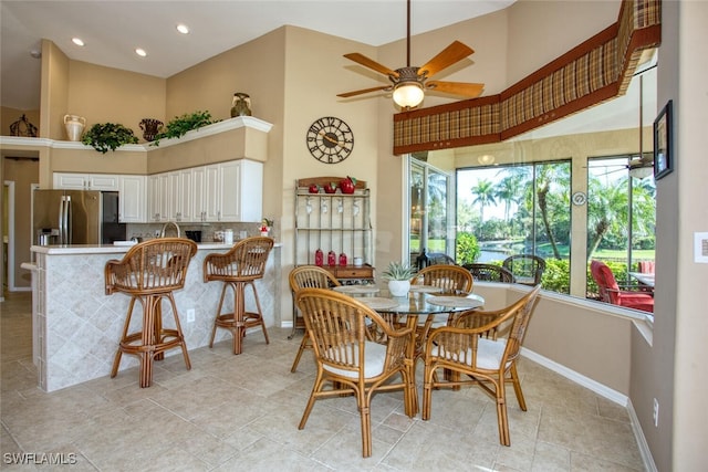 dining space featuring recessed lighting, baseboards, a high ceiling, and a ceiling fan