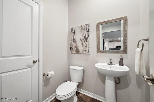 bathroom featuring a sink, baseboards, toilet, and wood finished floors