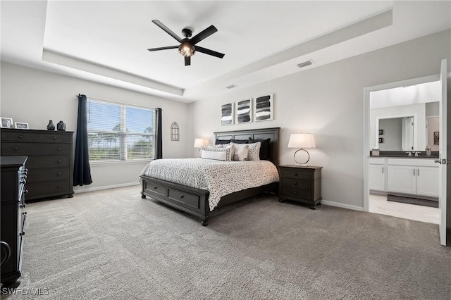 bedroom with light carpet, visible vents, a raised ceiling, and baseboards