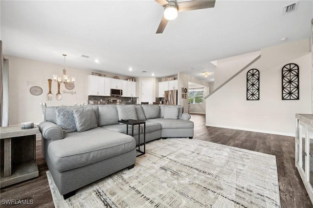 living area featuring visible vents, baseboards, recessed lighting, dark wood-style flooring, and ceiling fan with notable chandelier