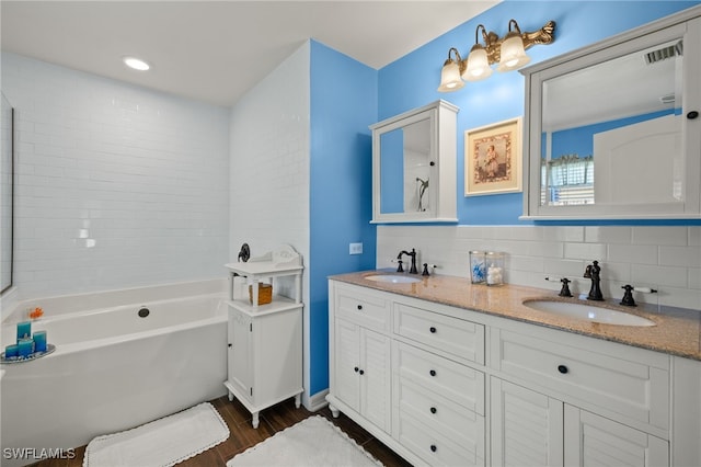 full bathroom with double vanity, a washtub, backsplash, and a sink