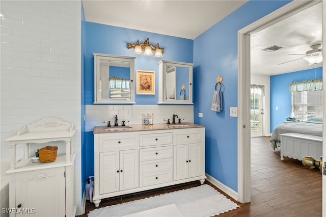 bathroom featuring connected bathroom, wood finished floors, visible vents, and a sink