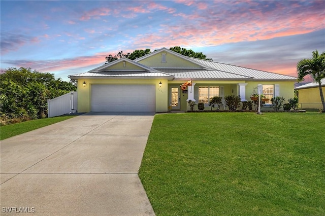 view of front of house with a standing seam roof, stucco siding, concrete driveway, a garage, and a lawn