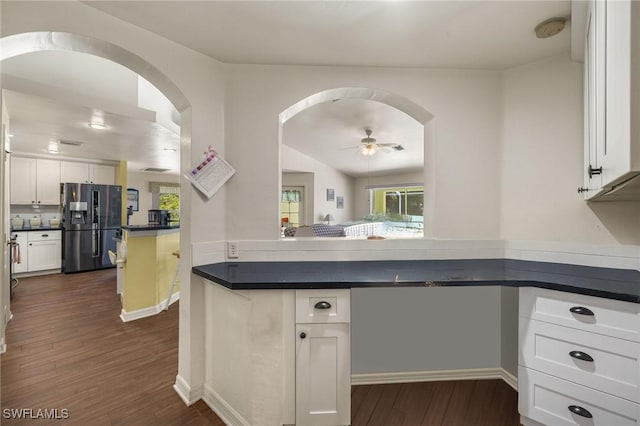 kitchen with white cabinetry, dark countertops, arched walkways, and black refrigerator with ice dispenser