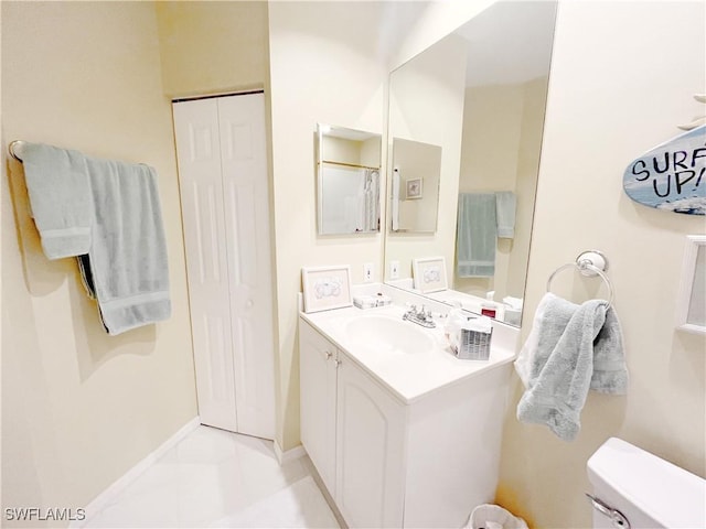 bathroom with toilet, baseboards, a closet, and vanity