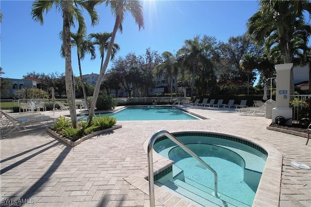 pool with fence, a patio, and a community hot tub
