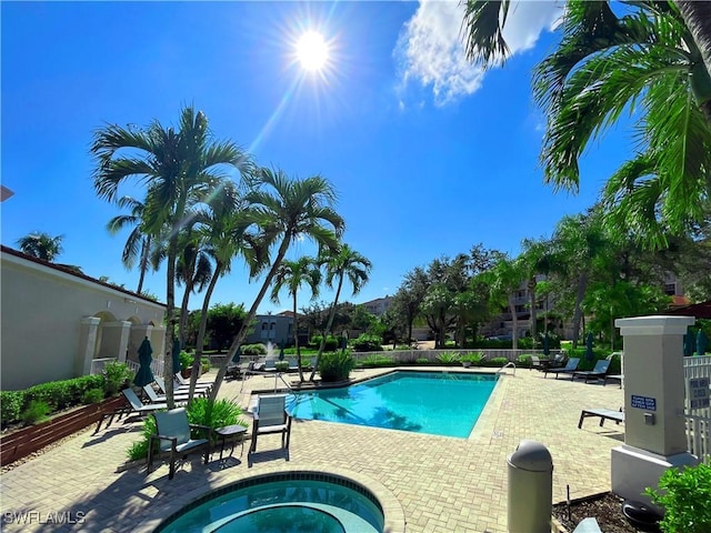 community pool with a hot tub and a patio
