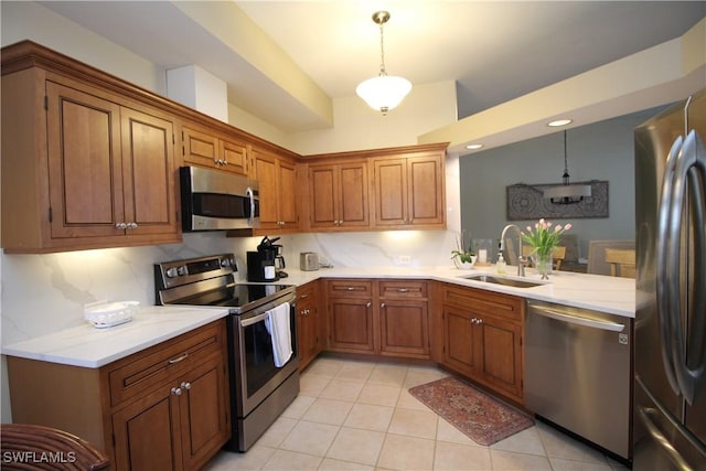kitchen with a sink, appliances with stainless steel finishes, brown cabinets, and light tile patterned flooring