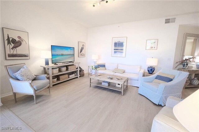 living area with visible vents, baseboards, and wood finished floors