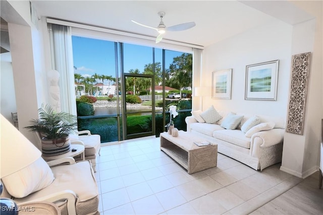 living area featuring a ceiling fan, baseboards, and a water view