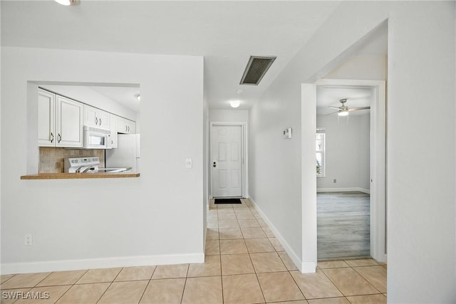 corridor with light tile patterned floors, baseboards, and visible vents