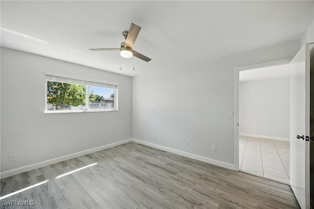 spare room featuring baseboards, wood finished floors, and a ceiling fan