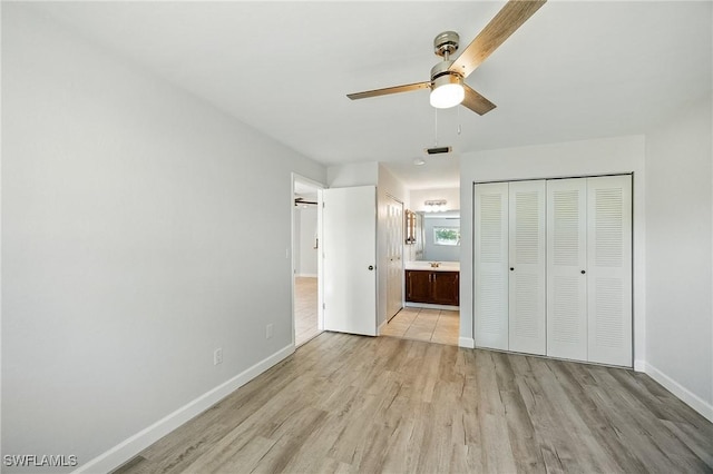 unfurnished bedroom featuring baseboards, ensuite bath, light wood-style flooring, and a ceiling fan