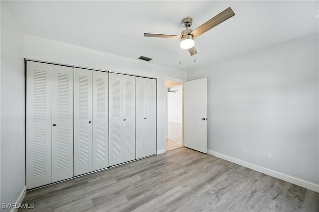 unfurnished bedroom featuring wood finished floors, visible vents, a closet, and baseboards