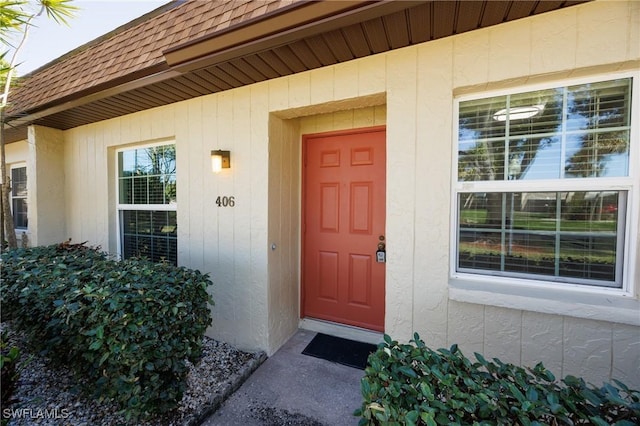 entrance to property with mansard roof and roof with shingles