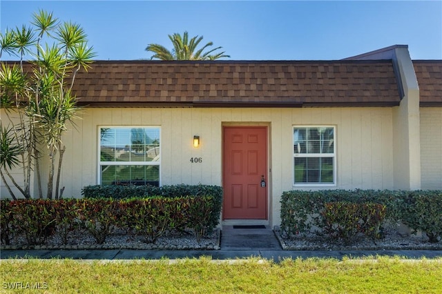 doorway to property featuring mansard roof and roof with shingles