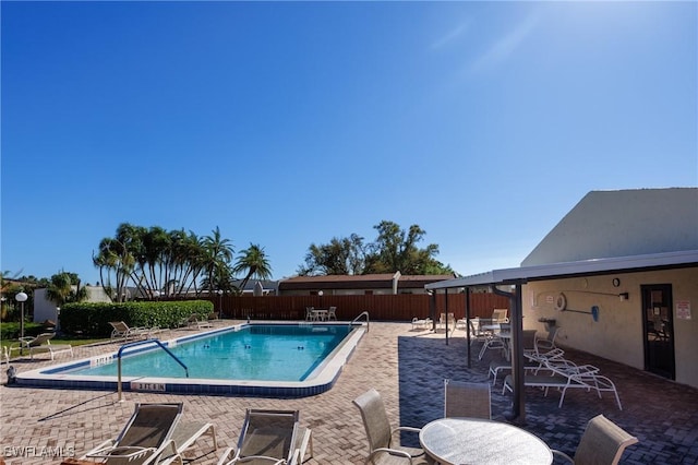 pool featuring a patio, outdoor dining area, and a fenced backyard