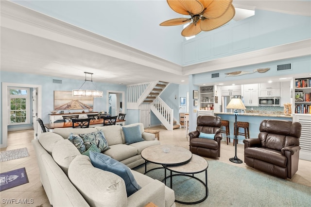 living area with light tile patterned floors, visible vents, stairs, and ceiling fan with notable chandelier