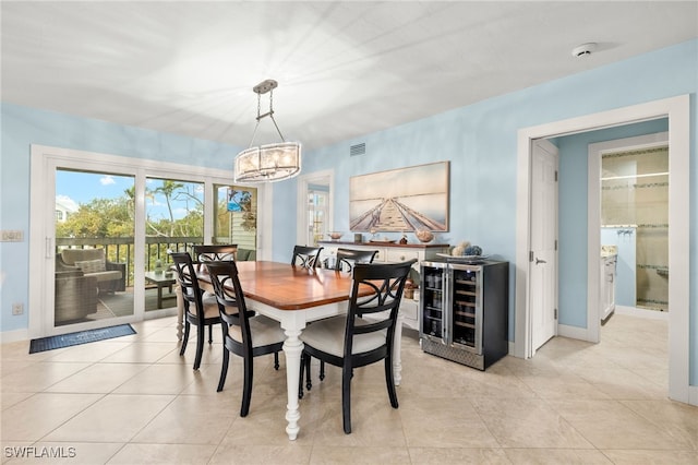 dining space with light tile patterned floors, baseboards, visible vents, wine cooler, and a chandelier