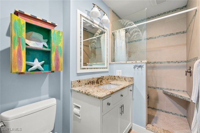 bathroom with toilet, vanity, and a tile shower