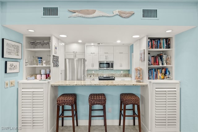 kitchen featuring stainless steel appliances, visible vents, and a peninsula