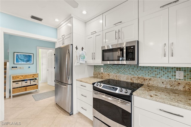 kitchen with light tile patterned floors, visible vents, stainless steel appliances, white cabinets, and backsplash