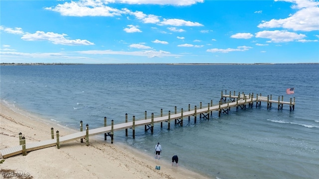 view of dock with a beach view and a water view