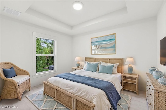 bedroom featuring a tray ceiling and visible vents