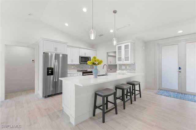 kitchen featuring a breakfast bar, stainless steel appliances, white cabinets, glass insert cabinets, and french doors