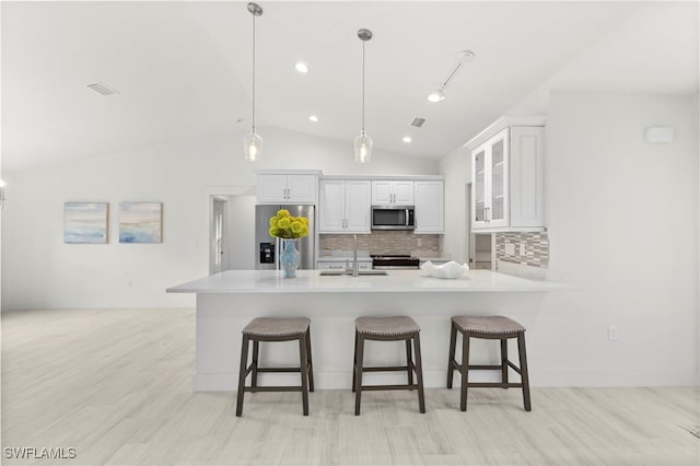 kitchen featuring a sink, a kitchen bar, appliances with stainless steel finishes, and decorative backsplash