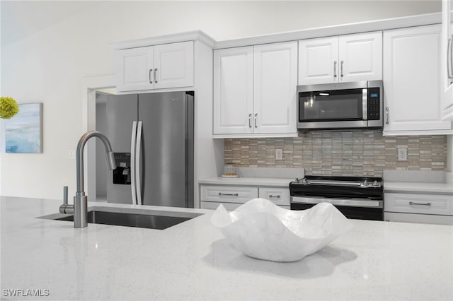 kitchen with tasteful backsplash, appliances with stainless steel finishes, white cabinetry, and a sink