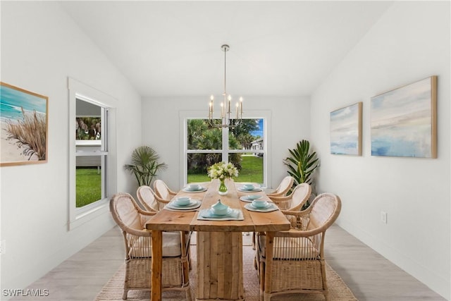 dining room with an inviting chandelier, lofted ceiling, and wood finished floors