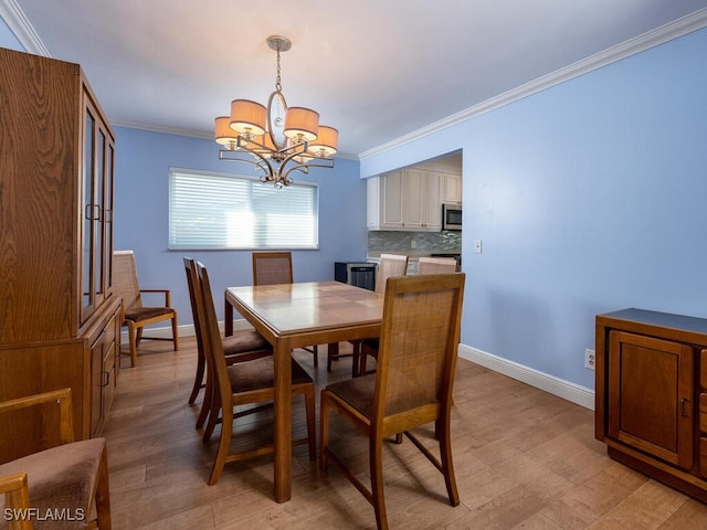 dining area featuring a chandelier, light wood-style flooring, baseboards, and ornamental molding