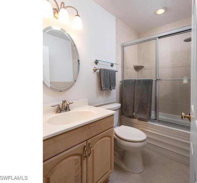 full bath with bath / shower combo with glass door, toilet, vanity, and tile patterned flooring