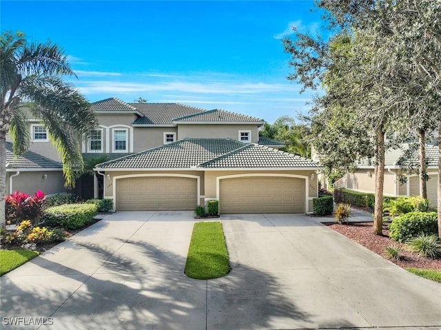 view of front of property with a tiled roof, a garage, driveway, and stucco siding