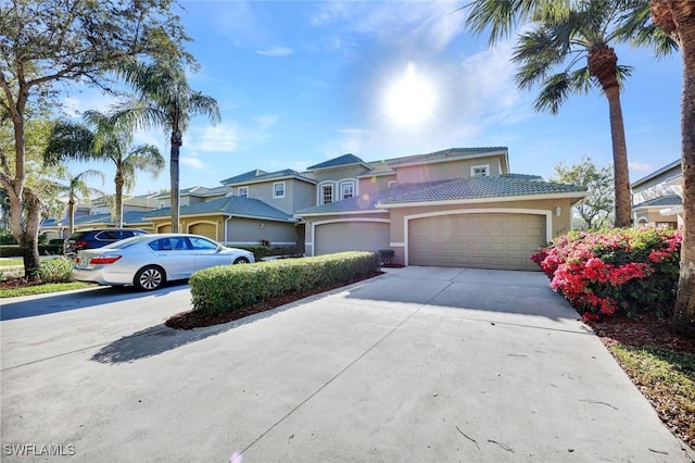 view of front of property featuring a tiled roof, stucco siding, driveway, and a garage