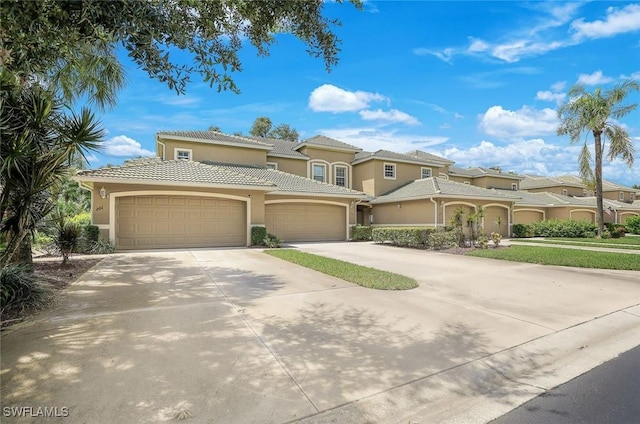 mediterranean / spanish home featuring stucco siding, a garage, driveway, and a tiled roof