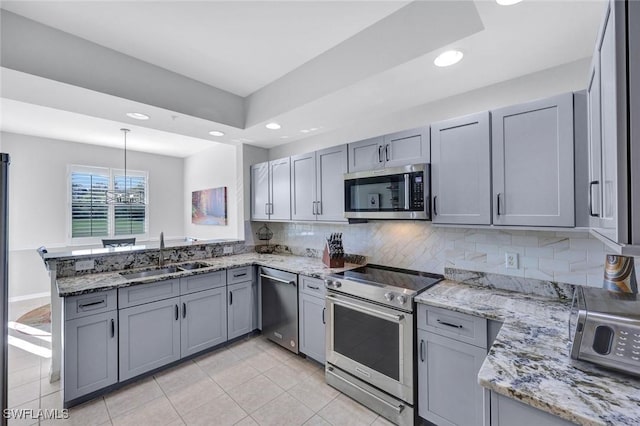 kitchen with tasteful backsplash, gray cabinets, a peninsula, stainless steel appliances, and a sink