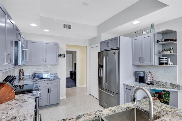 kitchen with visible vents, light stone countertops, light tile patterned floors, decorative backsplash, and stainless steel appliances