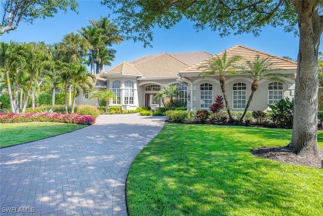 view of front of house featuring stucco siding, a tile roof, decorative driveway, and a front yard