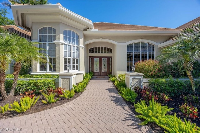 property entrance featuring a tiled roof, stucco siding, and french doors