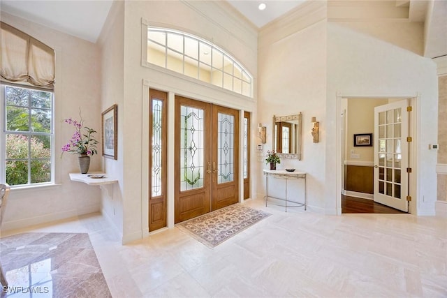 foyer entrance with french doors, baseboards, and a high ceiling