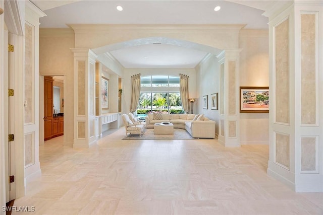 hallway with arched walkways, a decorative wall, recessed lighting, and crown molding