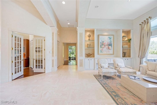 living area featuring a wealth of natural light, built in shelves, crown molding, and ornate columns