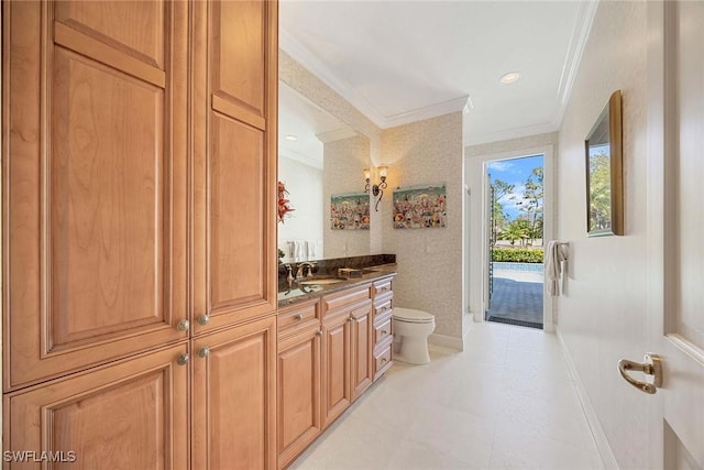 bathroom with baseboards, toilet, ornamental molding, and vanity