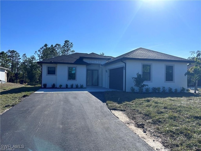 view of front of property featuring stucco siding, an attached garage, driveway, and a front yard