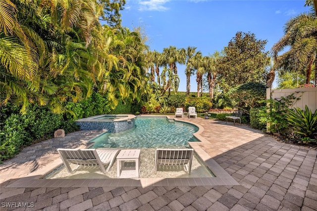 view of pool with a pool with connected hot tub, a patio, and fence