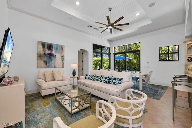 tiled living room featuring visible vents, baseboards, recessed lighting, arched walkways, and a raised ceiling